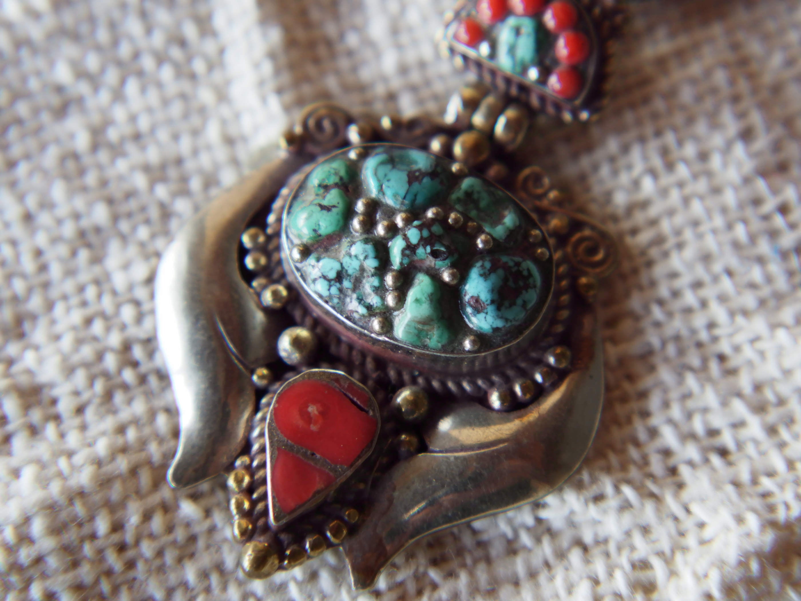 pendaglio tibetano / nepalese in argento con turchesi e corallo  pezzo unico lavorato artigianalmente tutto originale ed autentico .  cesellato ed inciso con i simboli del buon auspicio tibetano .  peso 24 gr  dimensioni 6x4x1 cm