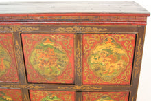 Carica l&#39;immagine nel visualizzatore di Gallery, Madia Tibetana A 6 Pannelli E 4 Ante Centrali, Costruita In Legno Di Foresta E Assemblata Ad Incastro, Interamente Originale E Conservata In Ogni Sua Parte. Databile Primi &#39;900, E&#39; Dipinta Su Legno Con Parti In Rilievo In Pasta Di Gesso. Mobile Ricco Di Raffigurazioni Di Derivazione Buddhista Come Il Leone Delle Nevi, Le Tigri, ecc...  Dimensioni 116x39xh100cm.