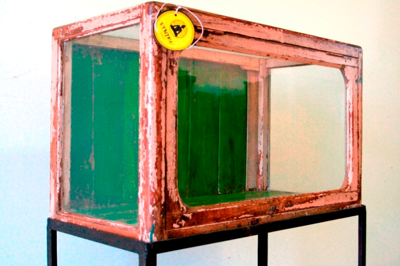 Vetrina, credenza , base indiana con basamento in metallo, vetro frontale e laterale. Usato come vetrina in negozio, apertura frontale a ribalta.  Dipinto interamente nella parte esterna la finitura è sbiancata, nella parte interna di verde intenso. Databile prima metà del '900. Pezzo unico. Dimensioni 75x40xh95cm. 
