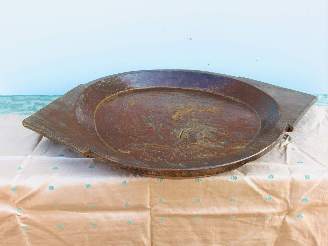 piatto in legno con manico ricavato da un unico tronco di legno. usato in principio come piatto , setaccio per esiccare i cereali . tronco unico di teak massello databile inizio / metà 900 .  dimensioni 75x54xh6cm.   disponibili vari modelli , contattare per info ed ulteriori foto info@etniko.it 0039 3338778241 fb/ig : etnikobycrosato