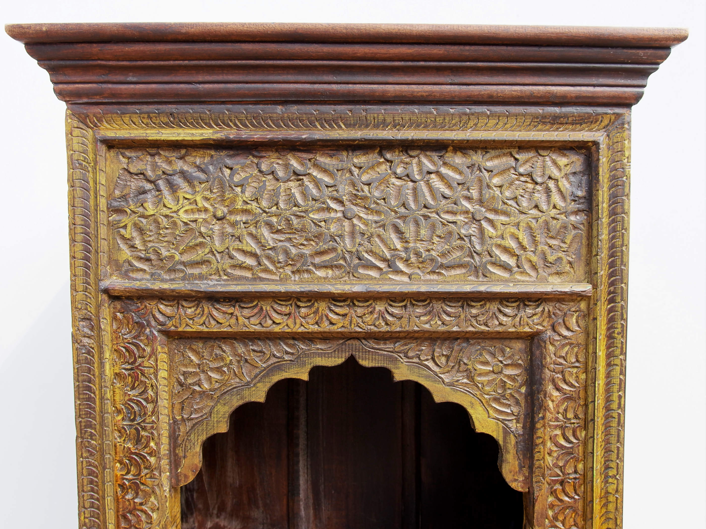 Dettaglio ravvicinato degli intagli floreali dorati e della cornice sagomata ad arco.