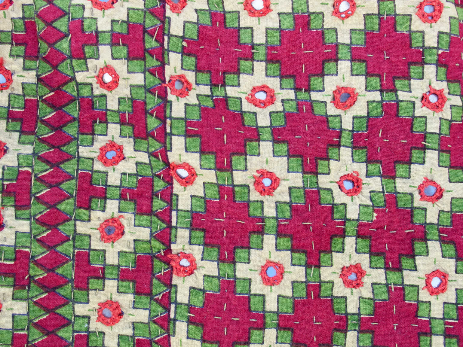 Tessuto print block ricamato in cotone con specchietti. I disegni geometrici sono di colore rosso, verde e panna, il retro è grigio. Può essere impiegato come copridivano, copriletto o tessuto da appendere a parete. Dimensioni 220x260cm