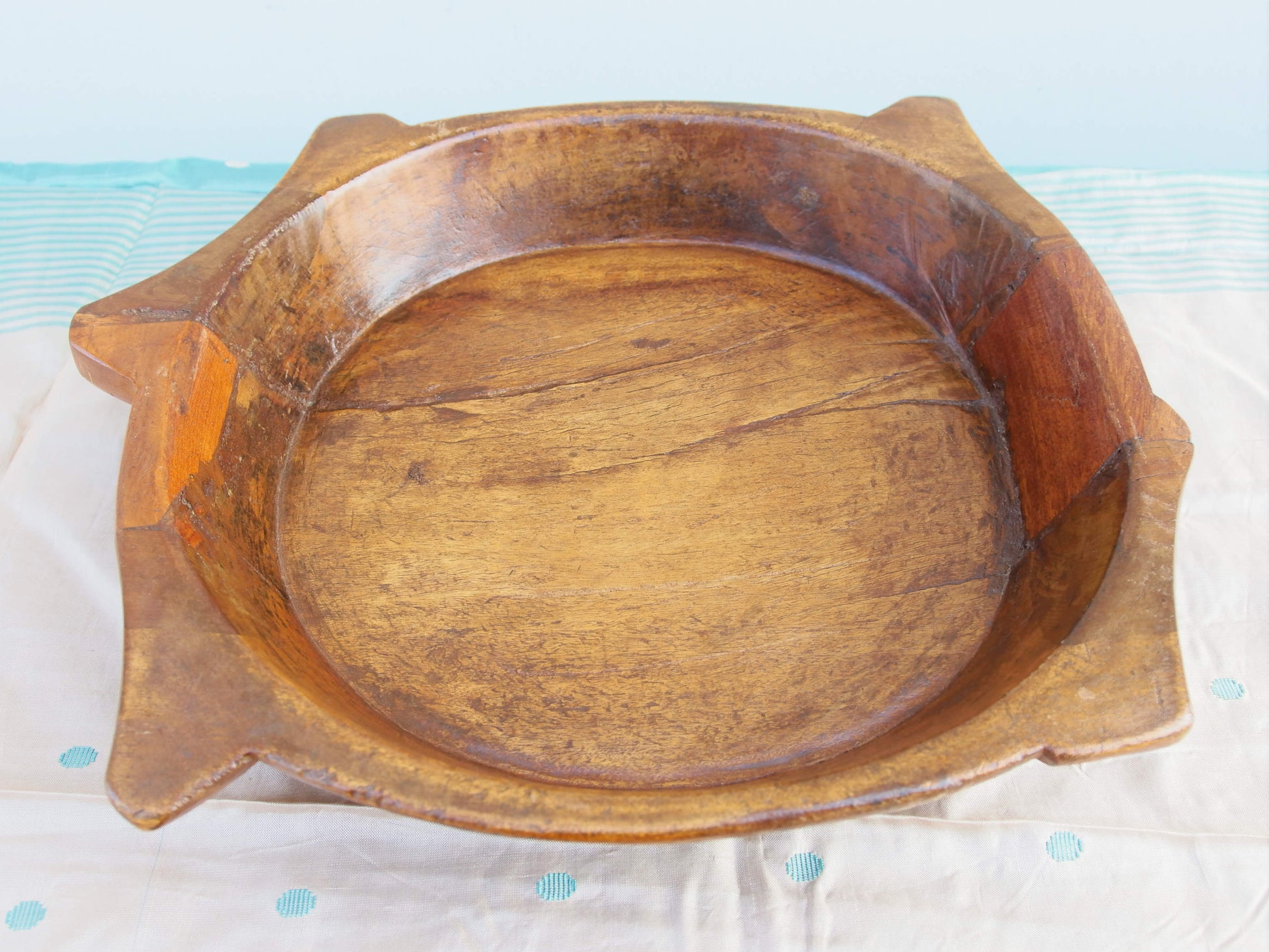 piatto in legno con manico ricavato da un unico tronco di legno. usato in principio come piatto , setaccio per esiccare i cereali . tronco unico di teak massello databile inizio / metà 900 .  dimensioni 35x38xh7cm.   disponibili vari modelli , contattare per info ed ulteriori foto info@etniko.it 0039 3338778241 fb/ig : etnikobycrosato