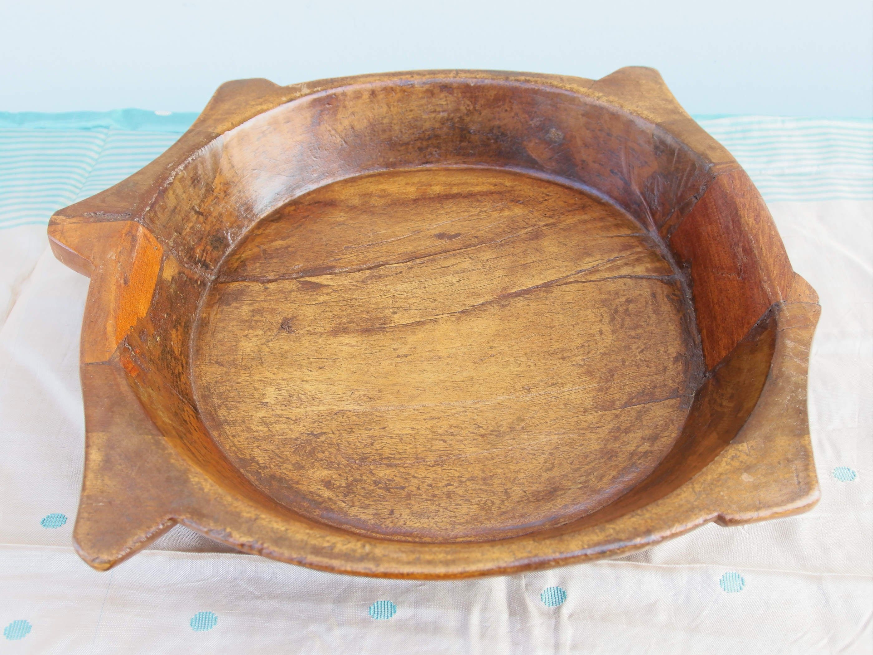 piatto in legno con manico ricavato da un unico tronco di legno. usato in principio come piatto , setaccio per esiccare i cereali . tronco unico di teak massello databile inizio / metà 900 .  dimensioni 35x38xh7cm.   disponibili vari modelli , contattare per info ed ulteriori foto info@etniko.it 0039 3338778241 fb/ig : etnikobycrosato