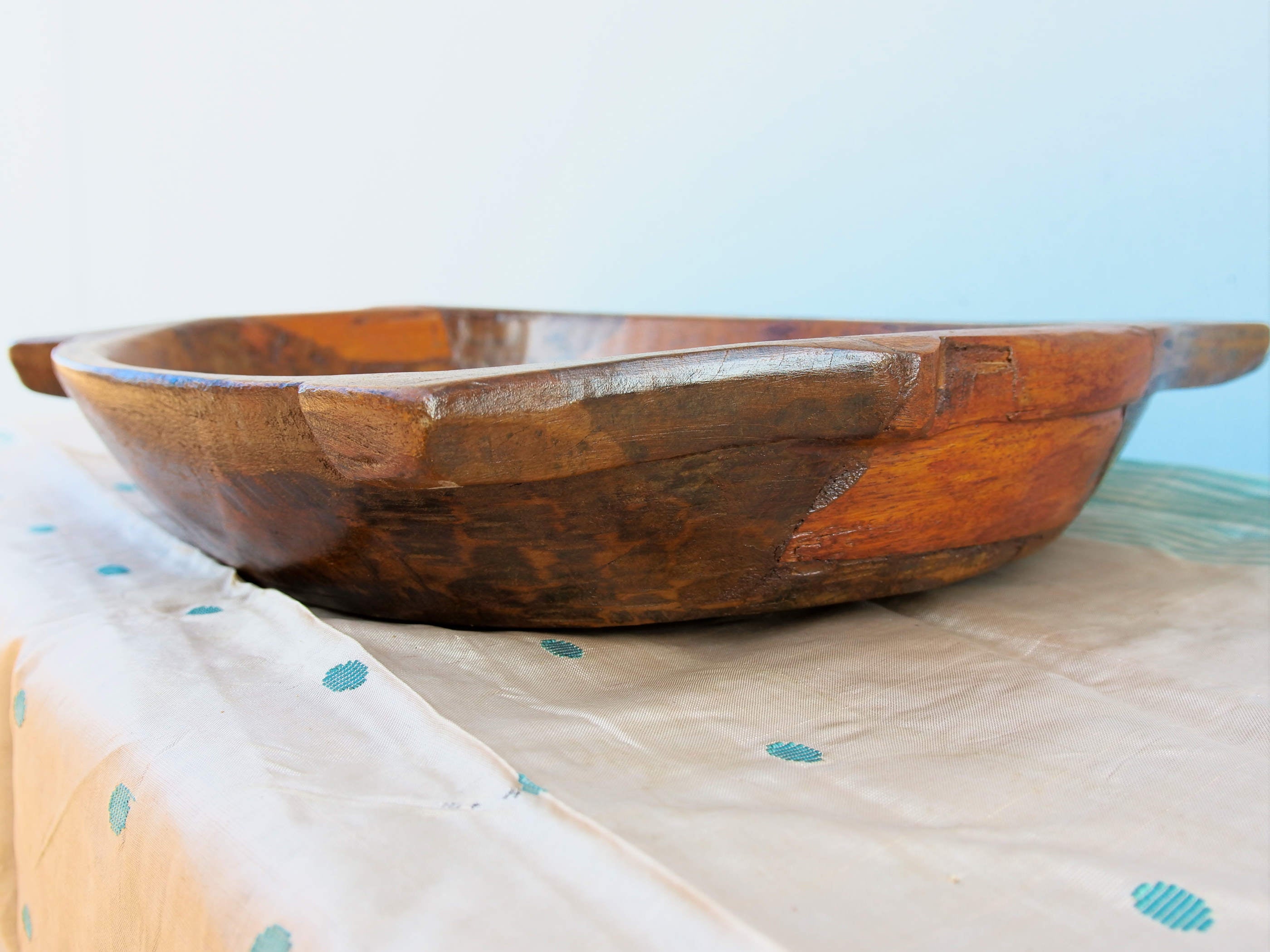 piatto in legno con manico ricavato da un unico tronco di legno. usato in principio come piatto , setaccio per esiccare i cereali . tronco unico di teak massello databile inizio / metà 900 .  dimensioni 35x38xh7cm.   disponibili vari modelli , contattare per info ed ulteriori foto info@etniko.it 0039 3338778241 fb/ig : etnikobycrosato