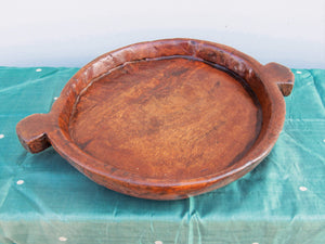 piatto in legno con manico ricavato da un unico tronco di legno.  usato in principio come piatto , setaccio per esiccare i cereali .  tronco unico di teak massello databile inizio / metà 900 .  dimensioni 40x54xh6cm.    disponibili vari modelli , contattare per info ed ulteriori foto info@etniko.it 0039 3338778241 fb/ig : etnikobycrosato
