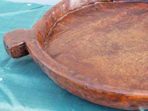 piatto in legno con manico ricavato da un unico tronco di legno.  usato in principio come piatto , setaccio per esiccare i cereali .  tronco unico di teak massello databile inizio / metà 900 .  dimensioni 40x54xh6cm.    disponibili vari modelli , contattare per info ed ulteriori foto info@etniko.it 0039 3338778241 fb/ig : etnikobycrosato
