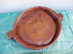 piatto in legno con manico ricavato da un unico tronco di legno.  usato in principio come piatto , setaccio per esiccare i cereali .  tronco unico di teak massello databile inizio / metà 900 .  dimensioni 40x54xh6cm.    disponibili vari modelli , contattare per info ed ulteriori foto info@etniko.it 0039 3338778241 fb/ig : etnikobycrosato