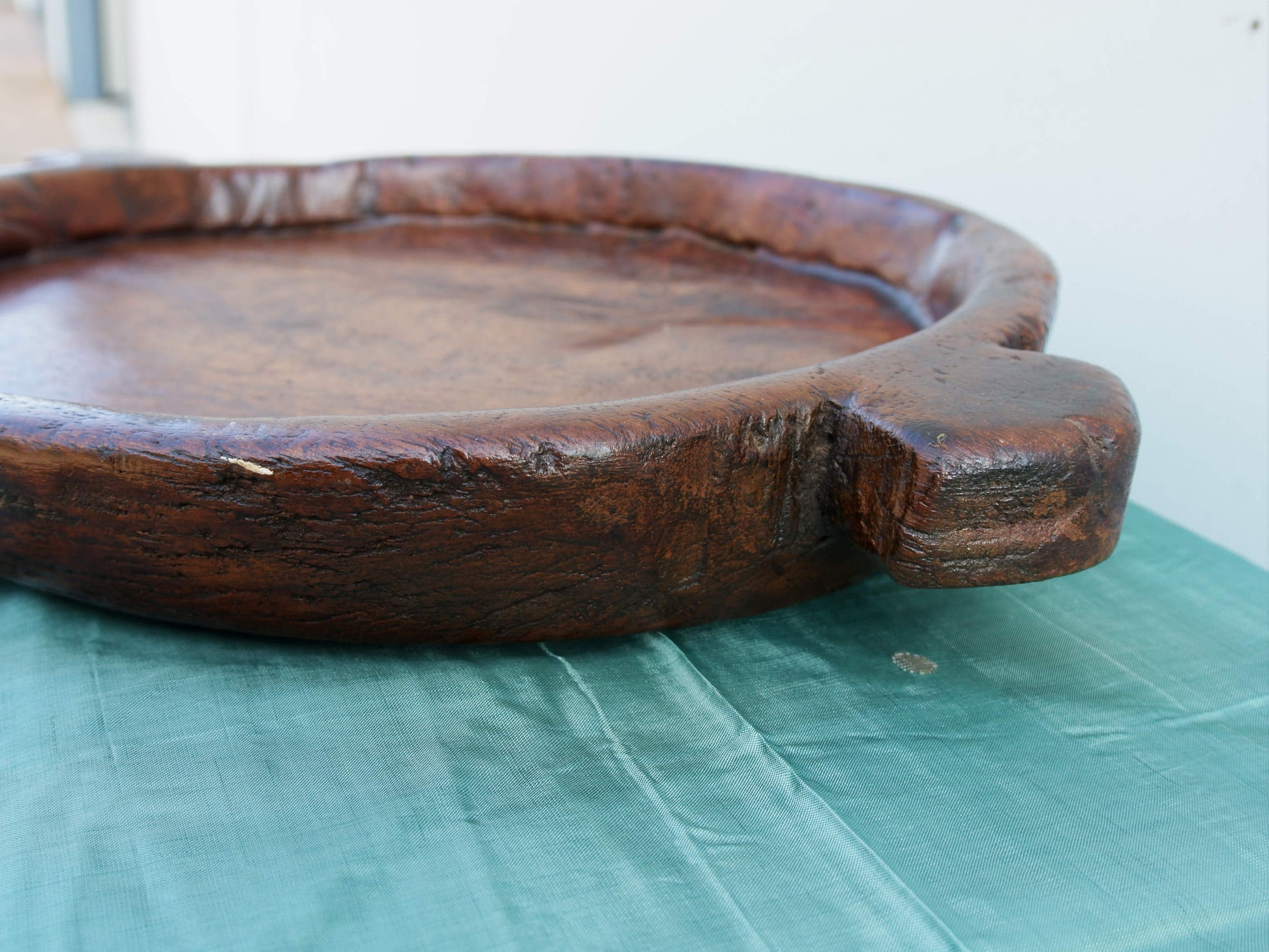 piatto in legno con manico ricavato da un unico tronco di legno.  usato in principio come piatto , setaccio per esiccare i cereali .  tronco unico di teak massello databile inizio / metà 900 .  dimensioni 40x54xh6cm.    disponibili vari modelli , contattare per info ed ulteriori foto info@etniko.it 0039 3338778241 fb/ig : etnikobycrosato