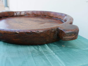 piatto in legno con manico ricavato da un unico tronco di legno.  usato in principio come piatto , setaccio per esiccare i cereali .  tronco unico di teak massello databile inizio / metà 900 .  dimensioni 40x54xh6cm.    disponibili vari modelli , contattare per info ed ulteriori foto info@etniko.it 0039 3338778241 fb/ig : etnikobycrosato