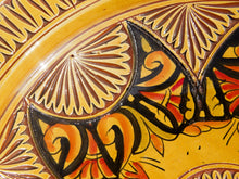 Carica l&#39;immagine nel visualizzatore di Gallery, Piatto marocchino decorato e dipinto in terracotta di Fes. La tradizionale terracotta di Fes é Impastata, decorata, cotta, smaltata e nuovamente cotta nel forno a legna (non nel forno a gas che rende lo smalto omogeneo e senza l&#39;effetto delle crepe). Decorato artigianlamente con i classici motivi berberi marocchini. Inserti in metallo inciso e pelle decorata. Pezzo Unico. Fori sul retro per poterlo appendere. Base per appoggio .  Dimensioni Diametro 35 h 8 cm