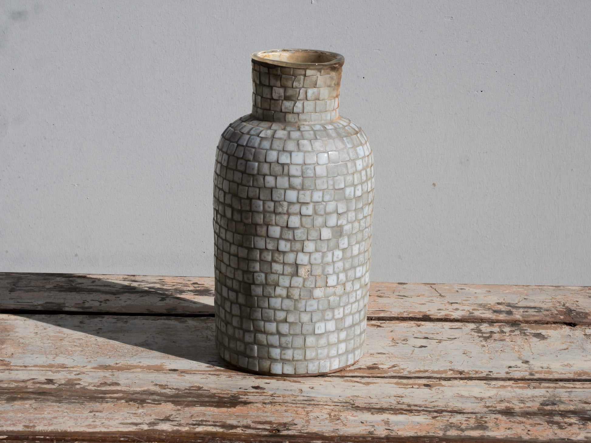 Vista frontale del vaso in vetro con decorazione a mosaico nei toni neutri.