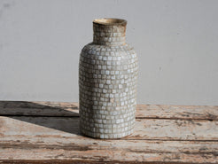 Vista frontale del vaso in vetro con decorazione a mosaico nei toni neutri.