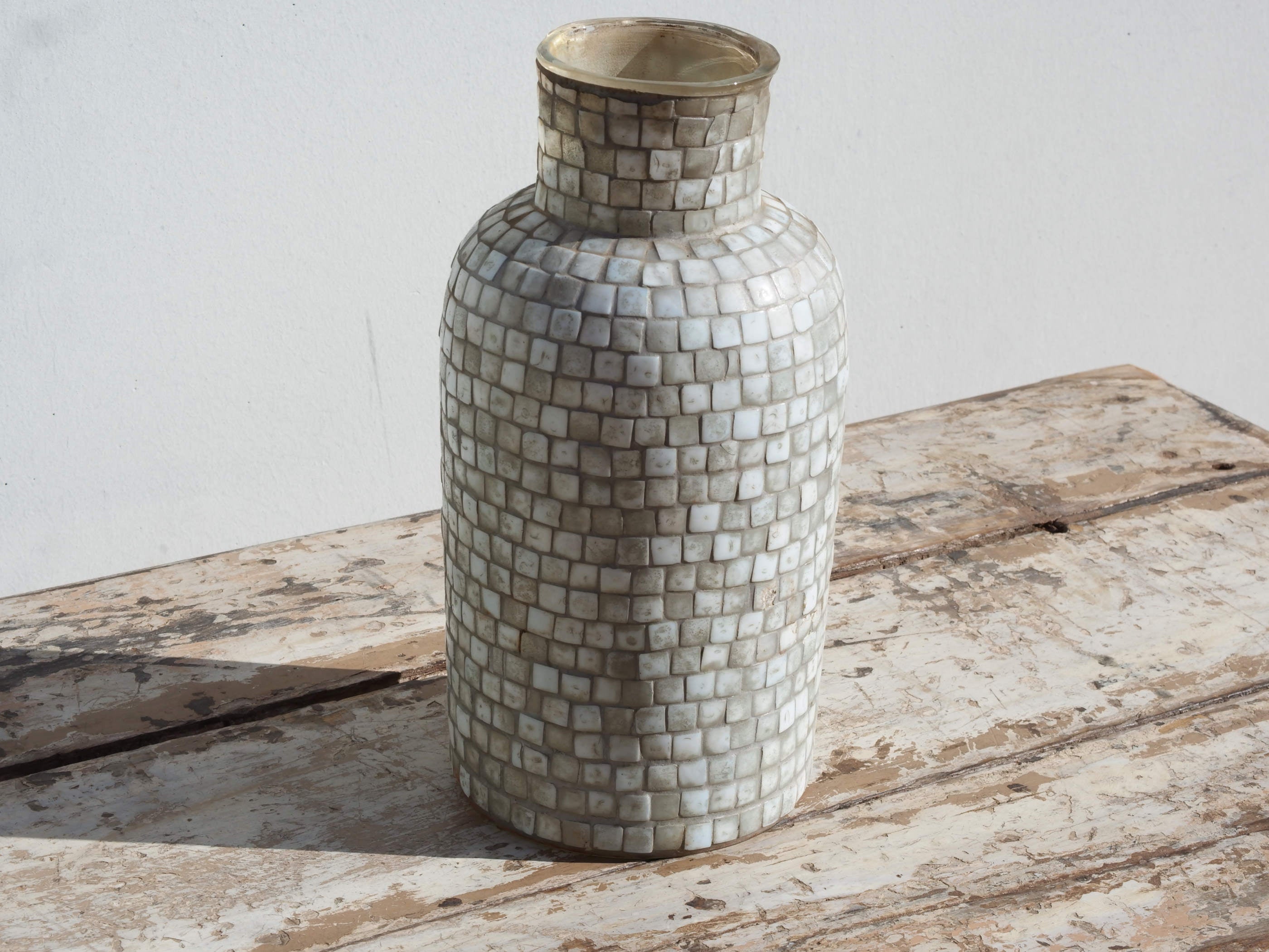 Vista frontale del vaso in vetro con decorazione a mosaico nei toni neutri.